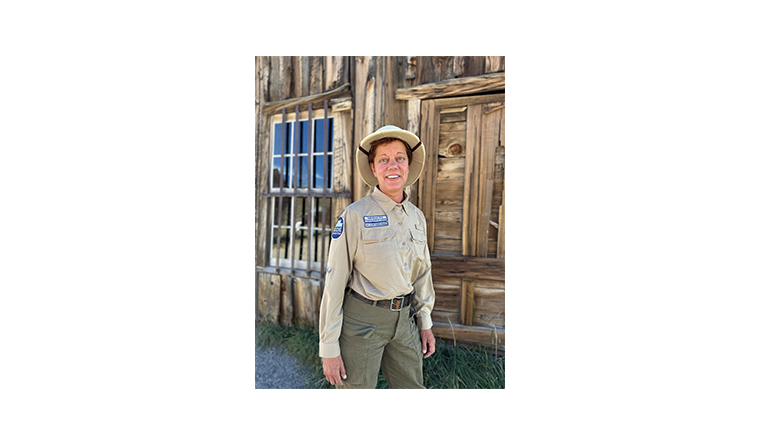 Dydia DeLyser stood in front of a wooden cabin