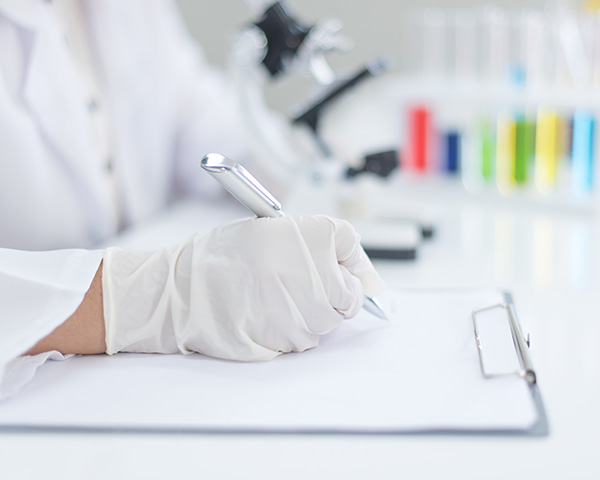 person wearing latex gloves writing notes on a paper