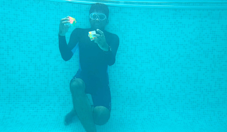 Person solving two puzzle cubes underwater