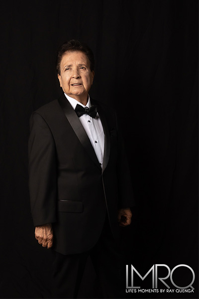 El Dana wearing a black suit looking over her shoulder